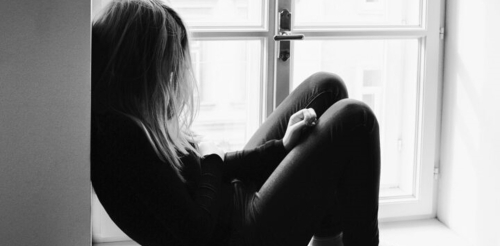 black and white image of sad woman in window