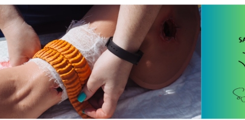 Close up of hands applying a bandage to a wounded arm