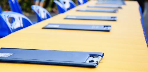 long table with clipboards and blue chairs