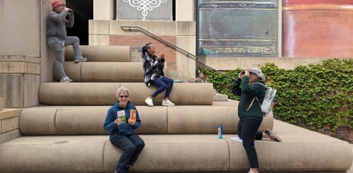 4 people near staircase which looks likes books