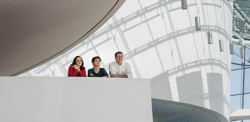 three people lean against balcony